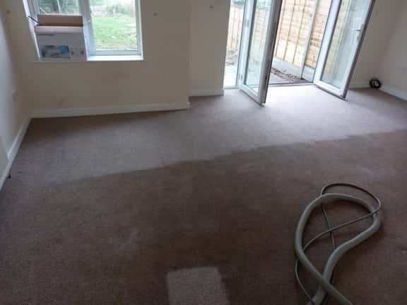 This is a photo of an empty living room with a brown carpet that is in the process of having its carpets steam cleaned works carried out by Belsize Park Carpet Cleaning Solutions